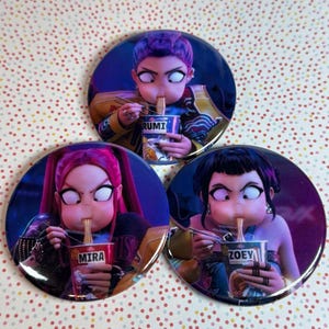 Może przedstawiać: Trzy okrągłe przypinki z postaciami w stylu anime jedzącymi makaron. Każda postać ma unikalną fryzurę i trzyma kubek z makaronem. Kubki są oznaczone jako "RUMI", "MIRA" i "ZOEY". Przypinki mają błyszczące wykończenie.