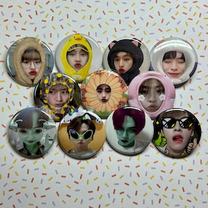 May include: Ten round pinback buttons featuring various cartoon characters with different expressions. The buttons are colourful and have a variety of designs, including a yellow alien, a green monster, a pink flower, and a blue and white striped shirt.