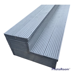 May include: A stack of gray composite decking boards with a grooved surface. The boards are arranged in a corner shape.