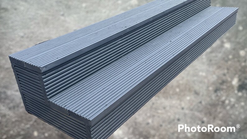 May include: Two-step gray plastic platform with a ribbed surface. The platform is designed for outdoor use.