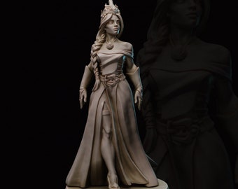 Könnte beinhalten: Eine weiß bemalte Miniaturfigur einer Frau, die ein langes, fließendes Kleid und eine Krone trägt. Sie hat langes Haar und hält ihre Hände vor sich. Die Figur steht auf einem runden Sockel.