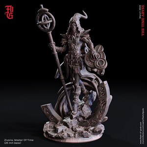 May include: A detailed miniature figure of a cloaked figure holding a staff with a circular orb on top. The figure is standing on a rocky base with swirling patterns and runes. The figure is painted in a dark bronze color.
