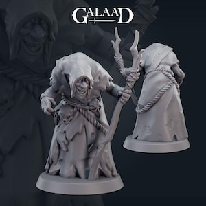 May include: A gray painted miniature figurine of a goblin wearing a hooded robe and holding a staff. The goblin has a large nose and a mischievous expression. The miniature is set on a round base.