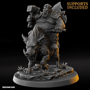Könnte beinhalten: Detaillierte 3D-Miniatur eines Orks, der auf einem Kriegsschwein reitet und einen Hammer und eine Axt hält. Der Ork ist schwer gepanzert und hat einen schädelartigen Helm. Das Wildschwein hat große Stoßzähne und greift an. Die Basis ist ein felsiges Gelände mit dem Text "SKULLFANG CLAN" und "SUPPORTS INCLUDED".