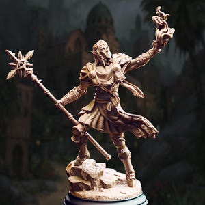 Può includere: Statuetta dettagliata di un personaggio fantasy, con in mano un bastone con una stella in cima e un oggetto fiammeggiante nell'altra. La figura è vestita con un'armatura e si trova su una base rocciosa, con uno sfondo sfocato di una città.