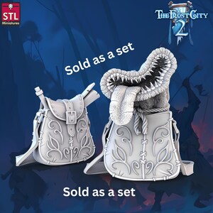 May include: Two white fantasy miniatures, a saddlebag and a monster head emerging from a bag, are displayed against a blue background. The saddlebag has a buckle and scroll. The monster head has a long tongue and sharp teeth. Text reads "Sold as a set".