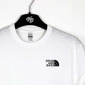 May include: White t-shirt with a black logo that says "Drum and Bass" in a mountain range design.