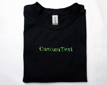 May include: Black t-shirt with a green, yellow, and black embroidered design that says "CustomText".