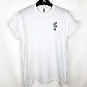 Peut inclure: T-shirt blanc avec un motif de champignon violet et vert sur le devant.