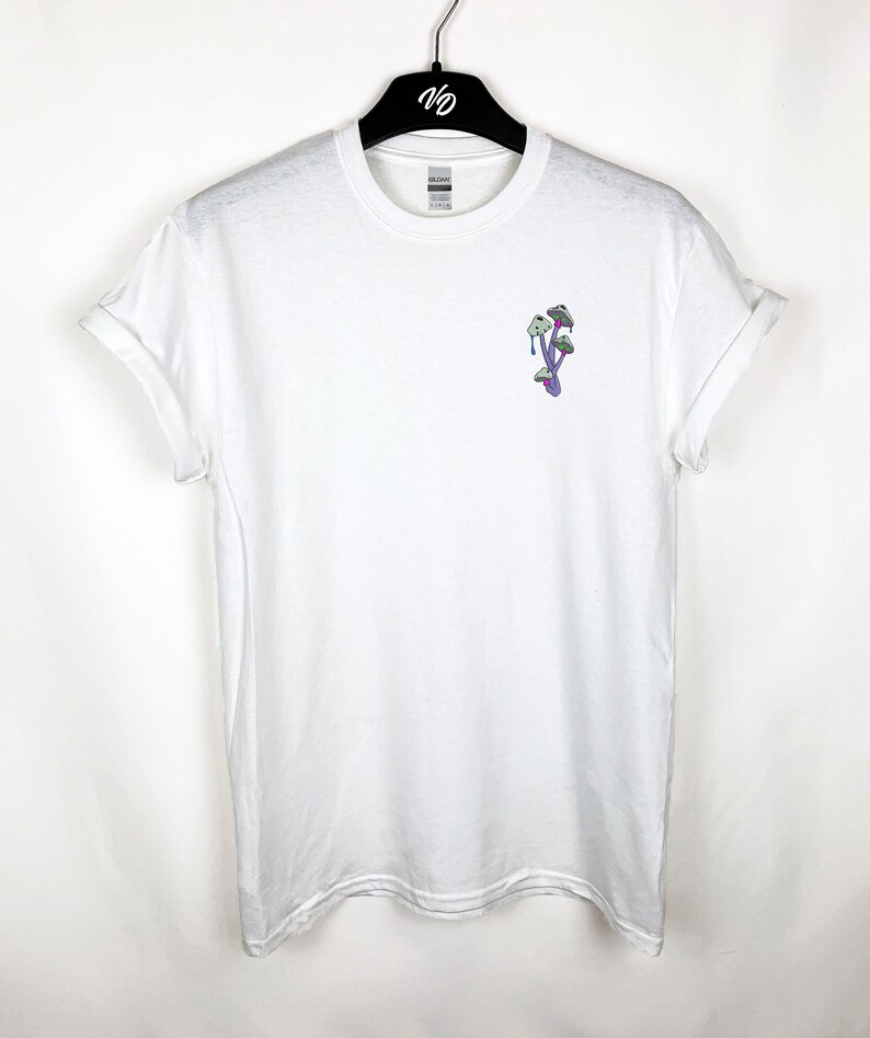 Peut inclure: T-shirt blanc avec un motif de champignon violet et vert sur le devant.