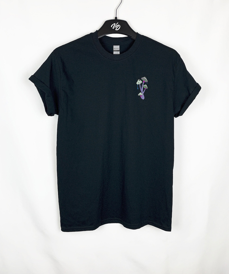 Peut inclure: T-shirt noir avec une petite image brod&eacute;e de champignons violets sur la poitrine gauche.
