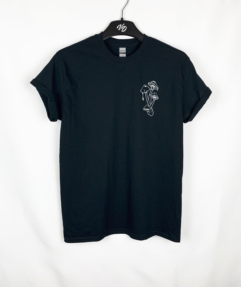 Puede incluir: Camiseta negra con un contorno blanco de setas en el pecho izquierdo.