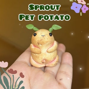 May include: A small, brown, potato-shaped figurine with green sprout ears and black eyes. The figurine is holding its arms in front of its body. The text "SPROUT PET POTATO" is written in green letters above the figurine.
