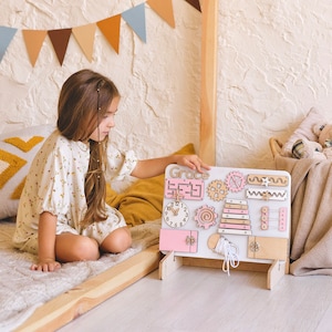 a little girl sitting on a bed playing with a toy