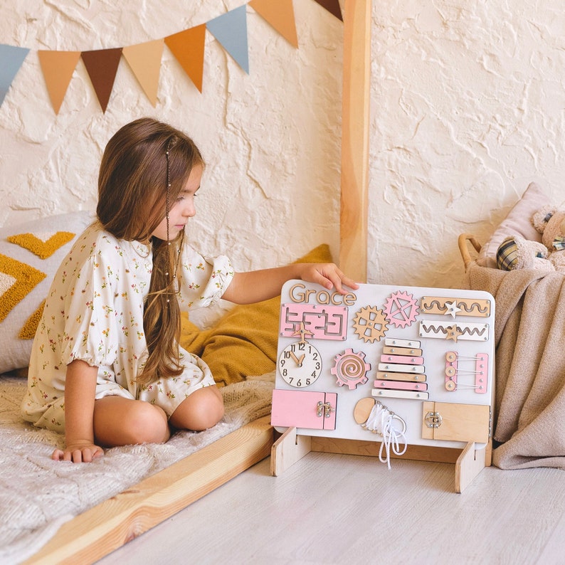 a little girl sitting on a bed playing with a toy