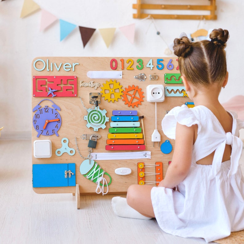 a little girl sitting on the floor playing with a wooden peg board