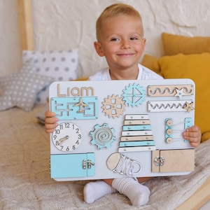 a little boy sitting on a bed holding a cut out of a laptop