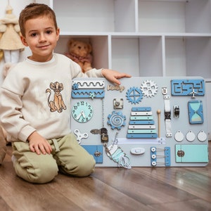 a young boy sitting on the floor with a toy