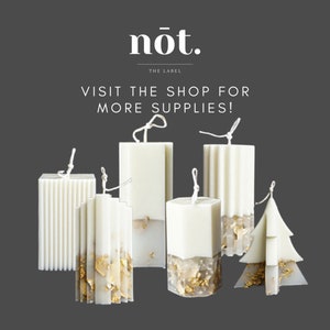 Op de afbeelding: Assortiment van witte kaarsen met gouden vlokken. De kaarsen zijn in verschillende vormen, waaronder rechthoekig, vierkant en een kerstboom. De tekst "n&oacute;t. THE LABEL VISIT THE SHOP FOR MORE SUPPLIES!" wordt boven de kaarsen weergegeven.