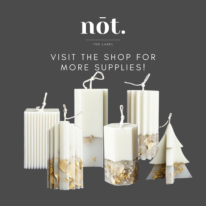 Op de afbeelding: Assortiment van witte kaarsen met gouden vlokken. De kaarsen zijn in verschillende vormen, waaronder rechthoekig, vierkant en een kerstboom. De tekst "n&oacute;t. THE LABEL VISIT THE SHOP FOR MORE SUPPLIES!" wordt boven de kaarsen weergegeven.