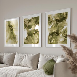 May include: A white sectional sofa with green throw pillows sits in a living room with three abstract paintings featuring green and gold swirls on a white background.