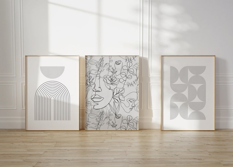 May include: Three framed prints with minimalist line art designs. The center print features a pattern of overlapping faces and floral elements. The print on the left features a gray arch with vertical lines. The print on the right features a pattern of overlapping gray circles.