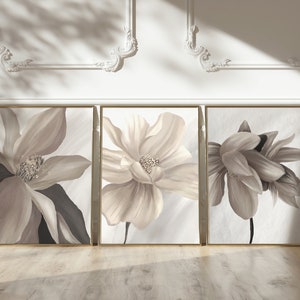 May include: Three framed floral prints with beige flowers on a white background. The frames are gold.