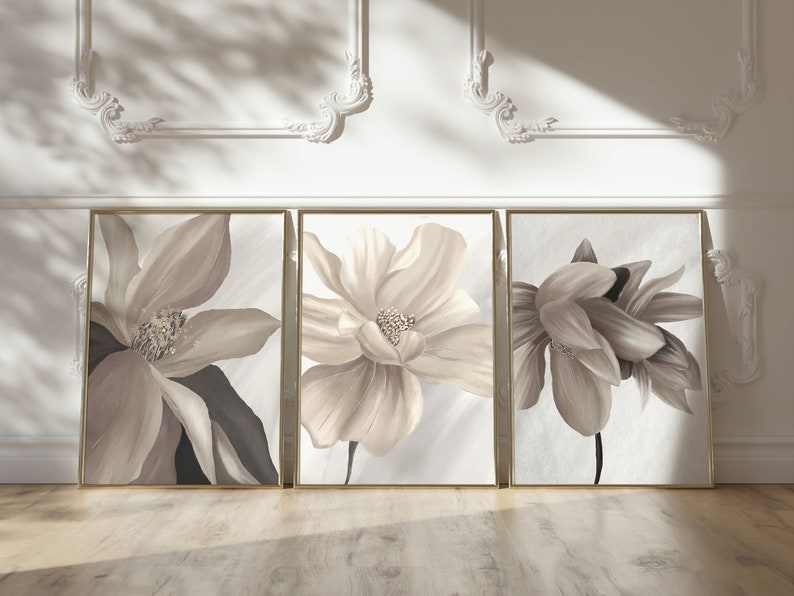 May include: Three framed floral prints with beige flowers on a white background. The frames are gold.