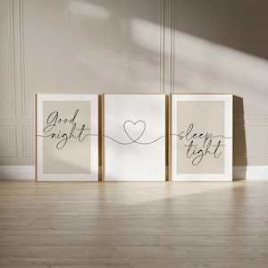 May include: Three framed wall art prints. The left and right prints have a beige background with the words "Good night" and "sleep tight" in black script. The center print has a white background with a black heart outline.
