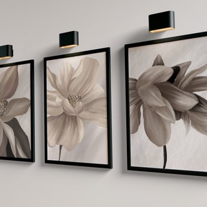 May include: Three framed floral prints with black frames. The prints feature close-up images of beige flowers with brown centers.