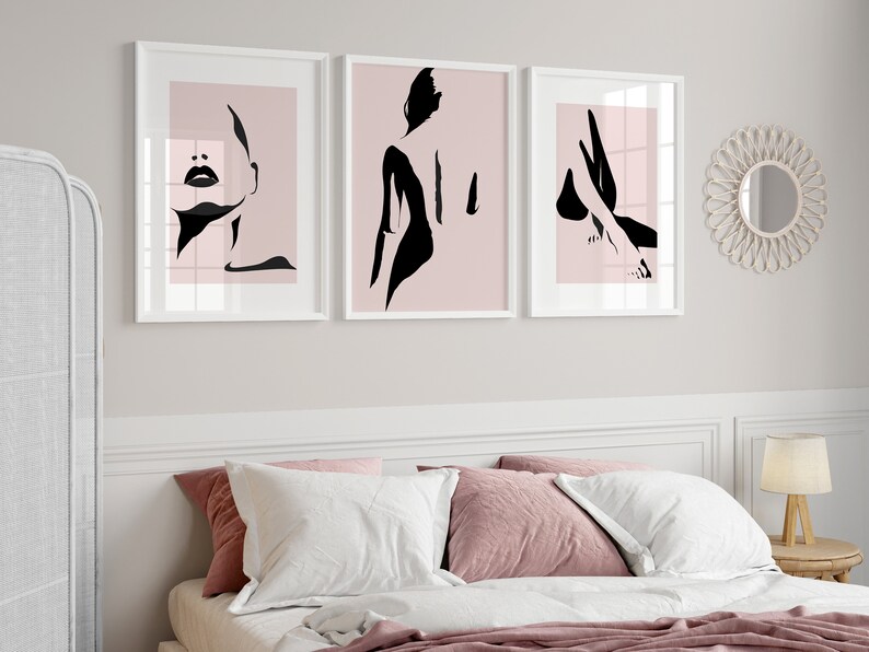 May include: Three framed wall art prints featuring black minimalist silhouettes of a human figure against a soft pink background. The first print shows a face, the second a back profile, and the third a leg, all displayed in white frames.
