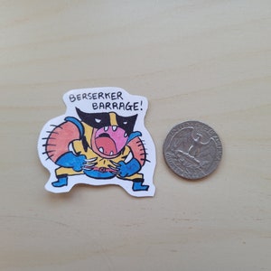 May include: A sticker featuring a cartoon illustration of Wolverine in a yellow and blue costume, with the text "Berserker Barrage!" above him.