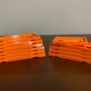 Peut inclure: Deux piles de cadres rectangulaires orange imprimés en 3D. Les cadres portent des inscriptions telles que "Neptune COR20 Pump", "EcoTech XR15 G4 PRO" et "VorTech MP40WQD". Ces cadres sont probablement destinés à des équipements d'aquarium.