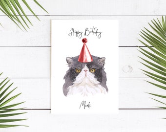 May include: A birthday card featuring a watercolor illustration of a gray and white cat wearing a red and white party hat. The card says "Happy Birthday Mark" in black script.