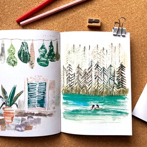 May include: An open sketchbook with two watercolor paintings. The left page features a row of green gourds hanging from a string. The right page shows a forest scene with a small boat on a lake.