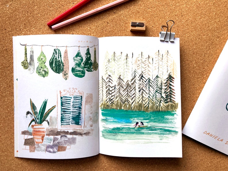 May include: An open sketchbook with two watercolor paintings. The left page features a row of green gourds hanging from a string. The right page shows a forest scene with a small boat on a lake.