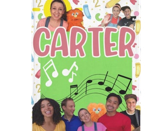 May include: A green and pink personalized book cover with the name "CARTER" in pink letters. The cover features a colorful background with musical notes, a sun, and a pencil. There are also images of children and a puppet.