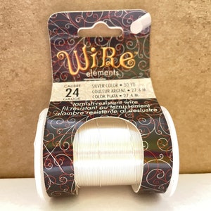May include: A spool of silver-colored, tarnish-resistant wire. The label reads "Wire elements", "Calibre 24 Gauge", "Silver Color - 30 YD", "Couleur Argent - 27.4 M", "Color Plata - 27.4 M", "Tarnish-resistant wire", "Fil resistant au ternissement", "Alambre resistente al deslustre".