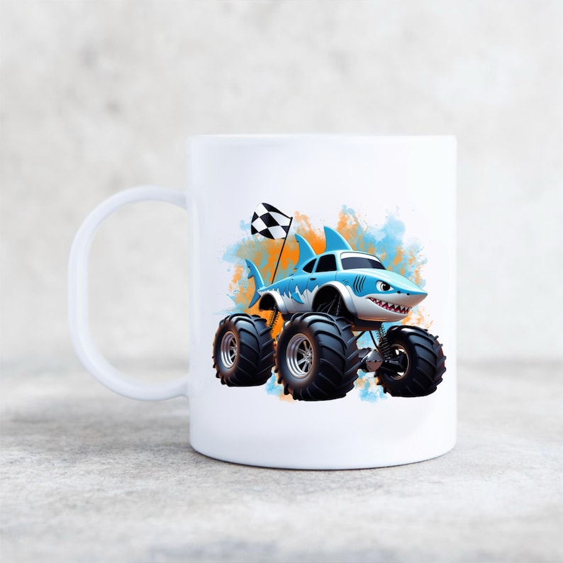 Peut inclure: Une tasse en c&eacute;ramique blanche avec un camion monstre de dessin anim&eacute; bleu et blanc avec des nageoires de requin et un drapeau &agrave; damier. Le camion est sur un fond aquarelle avec des &eacute;claboussures orange et bleues.