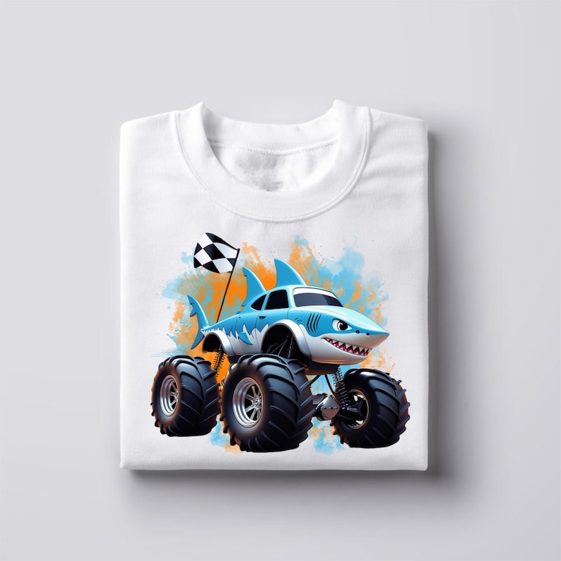 Peut inclure: T-shirt blanc avec un motif bleu et orange d'un camion monstre requin. Le camion a de grandes roues noires et un drapeau &agrave; damier.