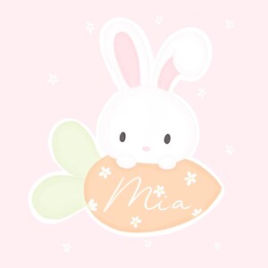 May include: A white bunny with pink ears sits on a carrot-shaped orange and white sign with the name "Mia" written in cursive. The background is a light pink with white flowers.