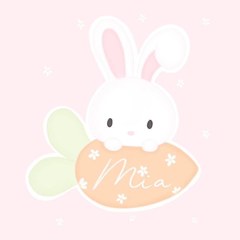 May include: A white bunny with pink ears sits on a carrot-shaped orange and white sign with the name "Mia" written in cursive. The background is a light pink with white flowers.