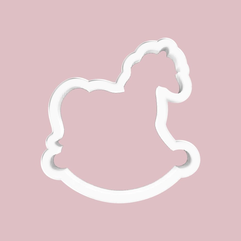 May include: A white, outline-style cookie cutter in the shape of a rocking horse. The cutter is set against a soft, pink background. The design features the horse's head, body, and curved rockers, perfect for baking themed treats.
