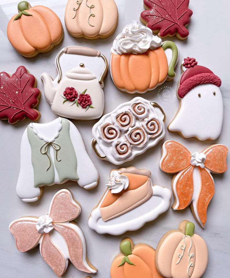May include: An assortment of decorated sugar cookies in fall and autumn themes. Cookies include pumpkins, fall leaves, a teapot, a ghost, a slice of pie, bows, and a mug of pumpkin spice latte.
