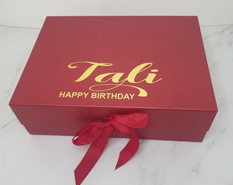 May include: A red gift box with a gold ribbon and the text "Tali Happy Birthday" on the top.