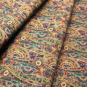 May include: A close-up of a folded fabric with a colorful, intricate pattern. The design features repeating circular and curved shapes in shades of blue, green, red, yellow, and purple. The fabric has a textured appearance.
