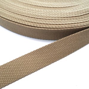 May include: A roll of brown cotton webbing, a type of flat woven fabric used for straps, belts, and other applications.