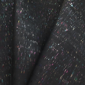 May include: Close-up of a black cork fabric with iridescent glitter accents. The fabric is folded, revealing its texture and the scattered, colorful specks. Ideal for crafting and design projects.