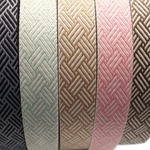 May include: Five different woven ribbon trims with a geometric pattern. The ribbons are black, light green, beige, pink, and brown.