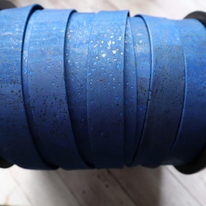 May include: A roll of blue cork ribbon with a speckled texture. The ribbon is wound around a black spool.